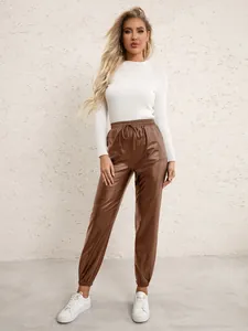 Model wearing white knit top and brown PU leather jogger pants with drawstring waist.