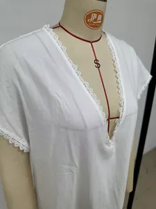 Close-up of white linen-cotton dress with delicate lace trim detail on V-neckline
