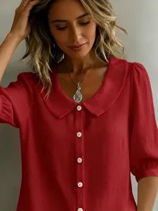 Detail einer roten Bluse in Leinenoptik mit Bubikragen und weißen Knöpfen für Damen.