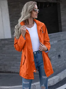 Side view of a woman wearing a vibrant orange hooded mid-length raincoat outdoors