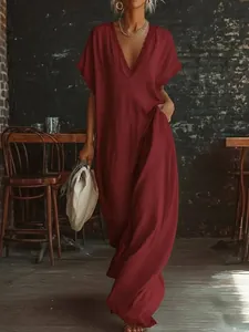 Elegant burgundy linen cotton maxi dress with lace trim shown in a warm cafe setting.