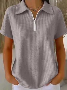 Détail d'un polo gris en maille gaufrée pour femme avec une fermeture éclair blanche courte