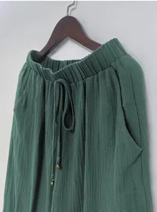 Close-up detail showing the texture and drawstring of green muslin wide-leg lantern pants