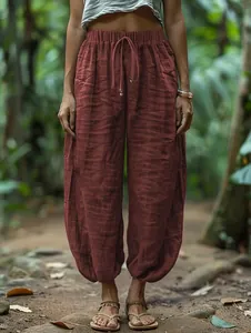 Detail of loose brick red lantern pants with elastic drawstring waist and linen texture.