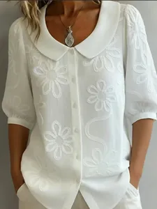 Gros plan d'une chemise vintage blanche avec col Claudine et broderies florales élégantes