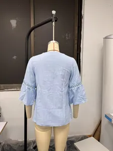 Vista posteriore della blusa in cotone e lino azzurro con pizzo sulle maniche a 3/4.