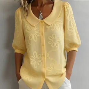Élégant chemisier jaune brodé de fleurs avec col Claudine et manches bouffantes.