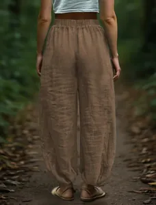 Detailed back view of brown loose cotton linen lantern pants in an outdoor forest path