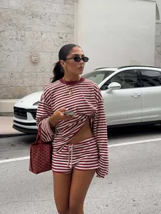 Model trägt ein rot-weiß gestreiftes Langarm-T-Shirt und ein passendes Shorts-Set.