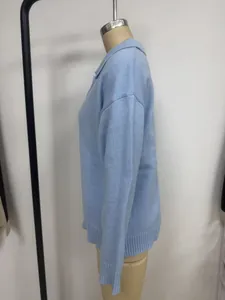 Detailed side profile of a light blue loose knit polo sweater with a ribbed hemline