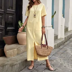 Dettaglio di un abito lungo giallo effetto lino con tasche frontali e spacco sull'orlo.