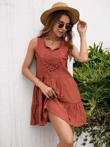 Detalle de un minivestido boho sin mangas con encaje y borlas en color naranja