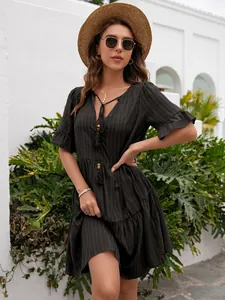 Bohemian black V-neck tiered dress with tassels shown in a sunlit outdoor setting