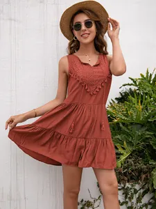 Vestido bohemio sin mangas rojo ladrillo con encaje y borlas en un entorno de jardín
