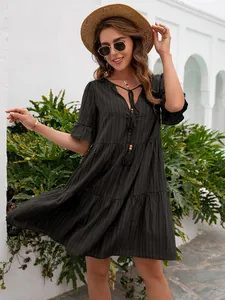 Model wearing a black loose V-neck dress with tassel details and short sleeves.