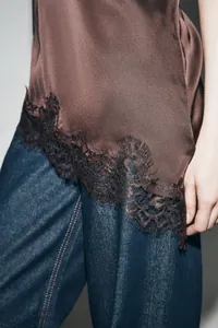 Detailed close-up showing the intricate black lace trim on a brown satin camisole top