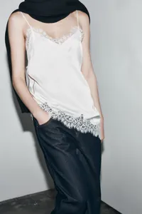 Detailed shot of elegant white silk camisole featuring delicate asymmetrical lace trim
