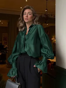 Elegante camisa de satén verde esmeralda con mangas de farol voluminosas en entorno de lujo.