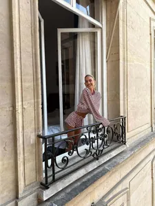 Frau im rot-weiß gestreiften Langarm-Top und Shorts-Set auf einem Balkon