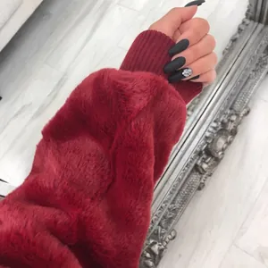 Gros plan d'une manche de manteau en fausse fourrure bordeaux avec poignets côtelés