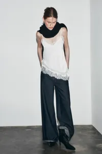 Close-up view of a white camisole featuring delicate lace trim on the hem and neckline