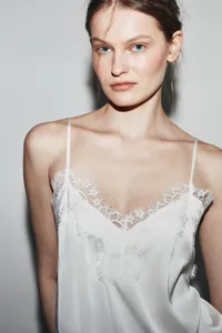 Close-up of white silk camisole featuring delicate floral lace trim at the neckline