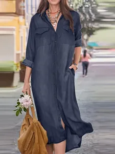 Full-length detail of a navy blue denim shirt dress featuring chest pockets and side slits
