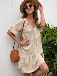 Casual beige V-neck tiered dress with ruffled half sleeves, paired with a straw hat.