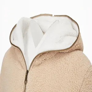 Gros plan d'une veste à capuche en polaire sherpa beige avec doublure blanche et fermeture éclair