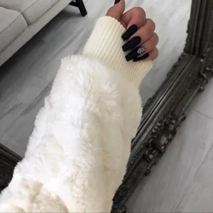 Détail montrant la texture douce du poignet en tricot d'un manteau en fausse fourrure blanc crème