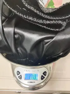 Close-up detail of women's black PU leather jogger pants showing weight on digital scale