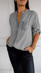 Detail of a grey long-sleeve casual shirt featuring a shimmering sequin-embellished pocket.
