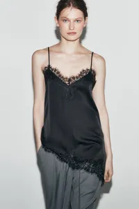 Detailed view of elegant black satin camisole with asymmetric eyelash lace trim