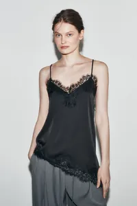 Detail view of black satin camisole with asymmetric lace trim and thin straps