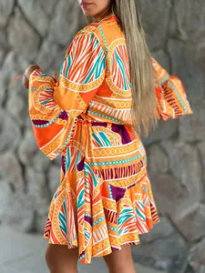Dettaglio laterale di un vestito arancione con maniche a campana e gonna a balze.
