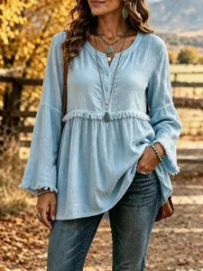 Close-up detail shot of light blue long sleeve V-neck blouse with white tassel fringe