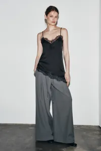 Close-up of black camisole with asymmetric lace hem and delicate lace neckline detail