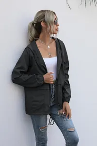 Outdoor view of a lightweight black hooded windbreaker jacket with zipper pockets