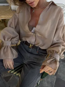 Detalle de una elegante camisa beige con mangas de linterna y solapa de corte holgado