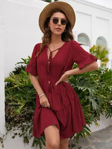 Elegant burgundy V-neck dress with ruffle sleeves and tassel details in outdoor setting.