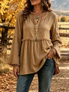 Close-up of a bohemian camel colored blouse with fringe detail and a V-neckline texture.
