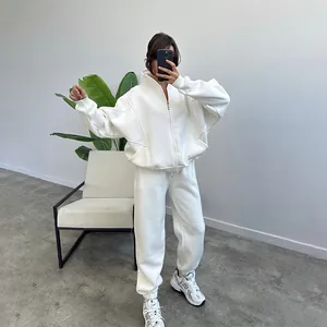 Full-body shot of a woman wearing a white oversized fleece zip-up hoodie and sweatpants.