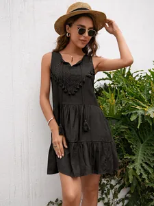 Detalle de un minivestido negro sin mangas con encaje y borlas para el verano.