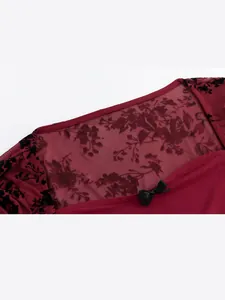 Detailansicht des zarten Spitzen-Mesh-Ausschnitts mit kleiner schwarzer Schleife auf weinrot