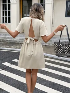 Vista posteriore di un mini abito beige chic con design senza schiena e elegante fiocco