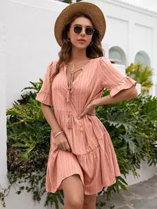 Detail showing the V-neck with tassels and ruffled sleeves of the peach casual dress