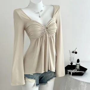 Détail d'un haut chic beige à manches longues et col en V avec devant froncé
