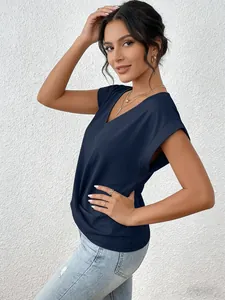 Elegant navy blue V-neck short sleeve top worn by model against white wall.