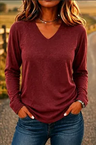 Close-up of a women's casual burgundy V-neck long-sleeve T-shirt in sunset light.