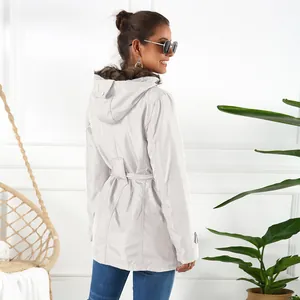 Woman wearing a mid-length grey winter coat with a faux fur collar and belt, back view